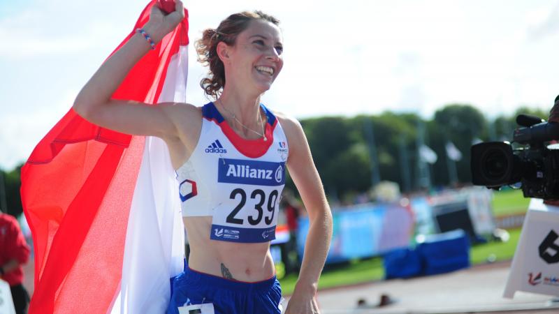 Women on a track celebrating with a French flag