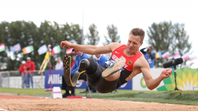 Man in the long jump right before landing in the sand