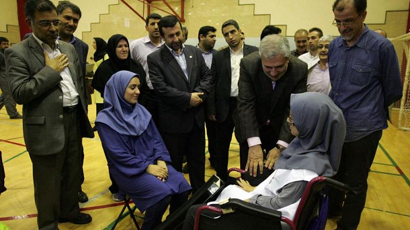 Men in suits in a conversation with two women in wheelchairs