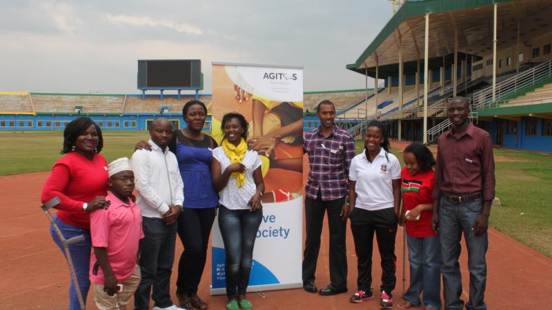 A group of people pose in front of an Agitos Foundation pull-up