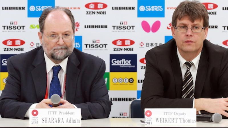 Two men on a press conference podium.