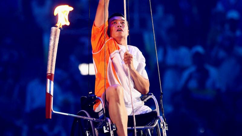 Hou Bin climbing up a rope in a wheelchair.