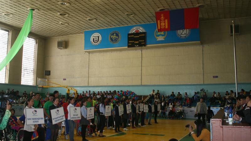 Many people in a room with some holding white signs