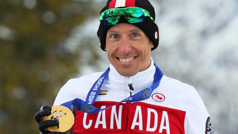 Upper body of smiling man holding medal