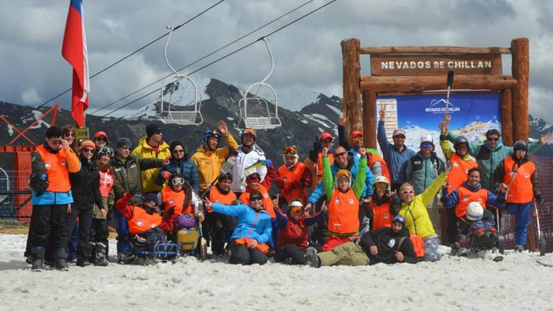 Group of skiers with different impairments in front of a sign saying "Nevados de Chillan"