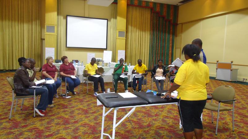 10 people in a workshop around a table with one person explaining.