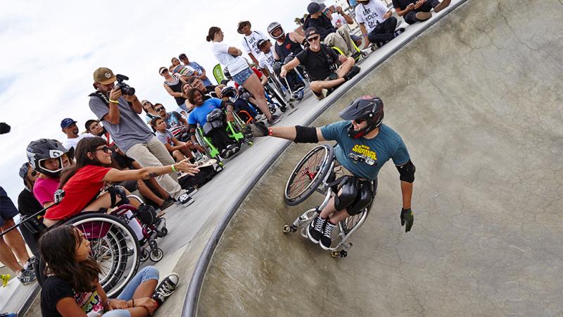Man in wheelchair doing a stund in a halfpipe