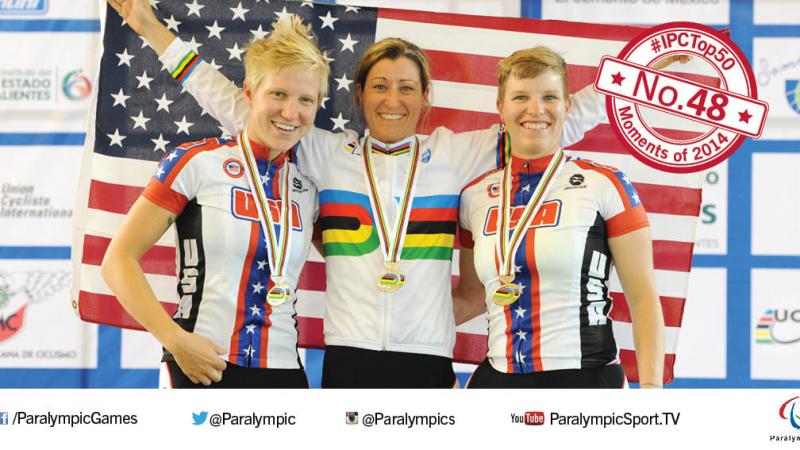 Three women on a podium, smiling to the camera