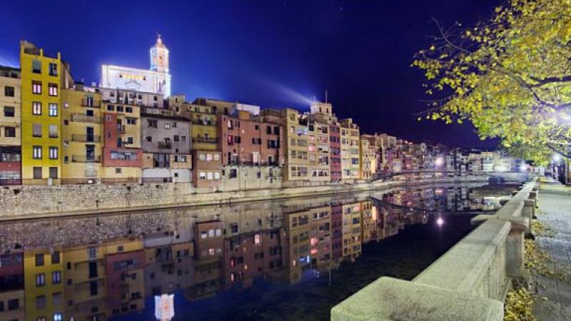 A night time shot of a river bank with stunning buildings in the background.