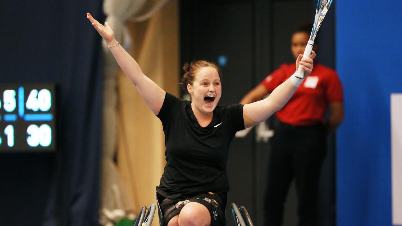 Women in wheelchair holding tennis racket, celebrating