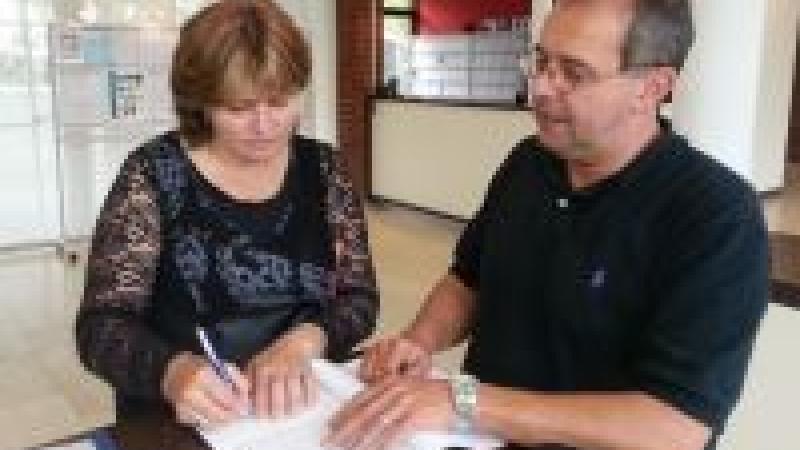 Man and woman sign a form standing on a table