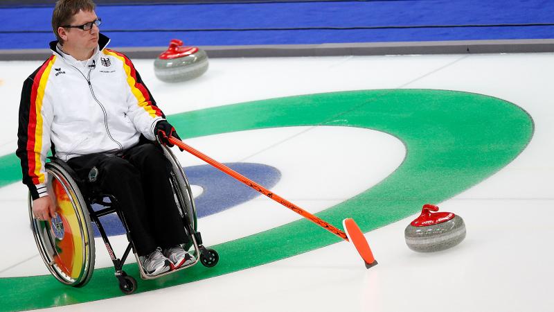 Man in wheelchair on the ice, pointing on a point on the ice