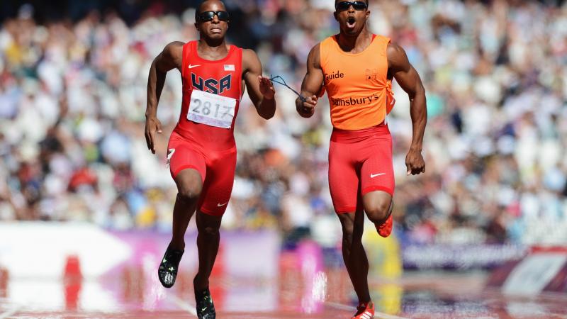 Runner and guide run in a full stadium