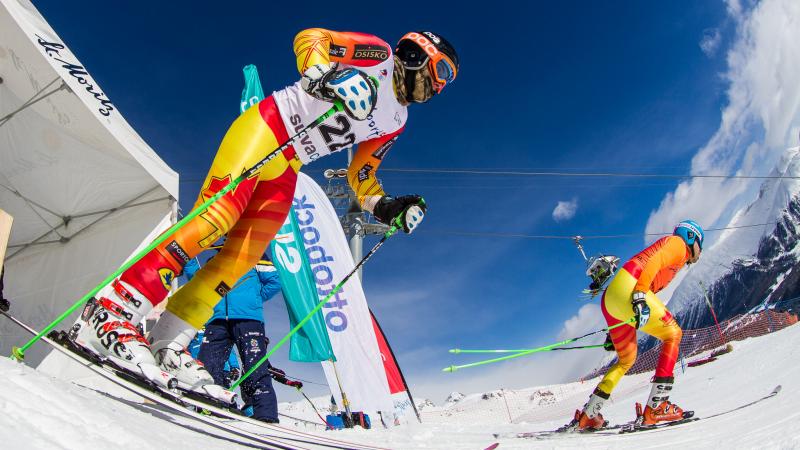 Two skiers starting from a start house on a ski slope