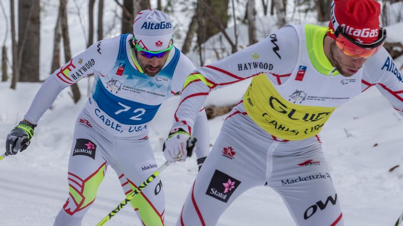 cross country skier and guide climb up a hill
