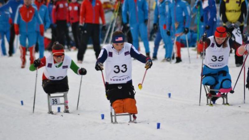 female athlete in a sit ski propelling herself forward