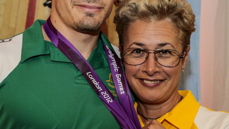 Women and man pose with a medal