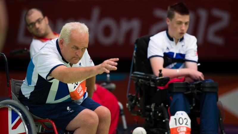 Two men in wheelchairs on a boccia field of play