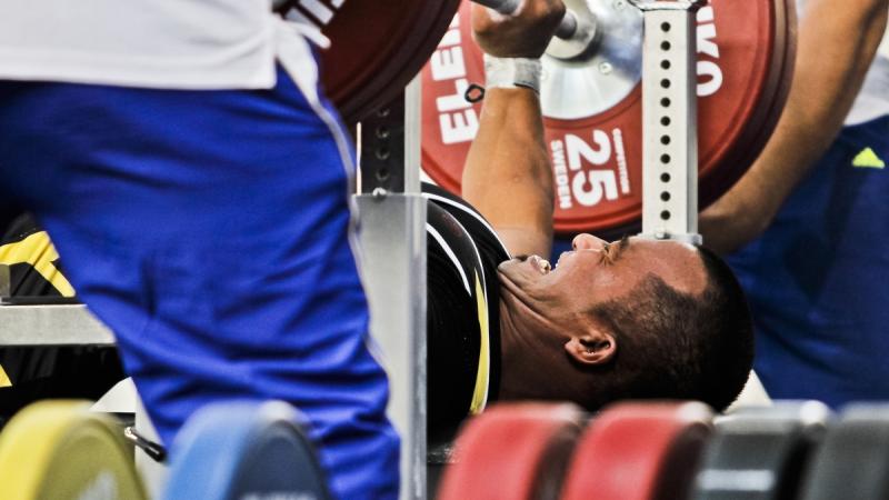 A powerlifter tries to lift the bar.