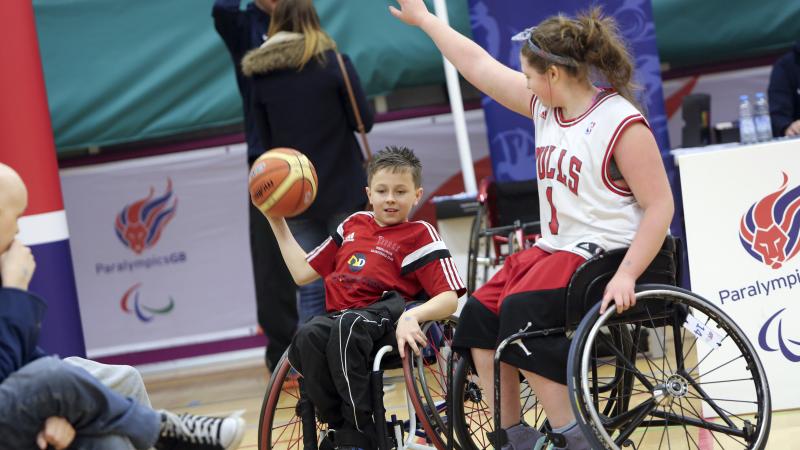 Two people in wheelchair playing basketball