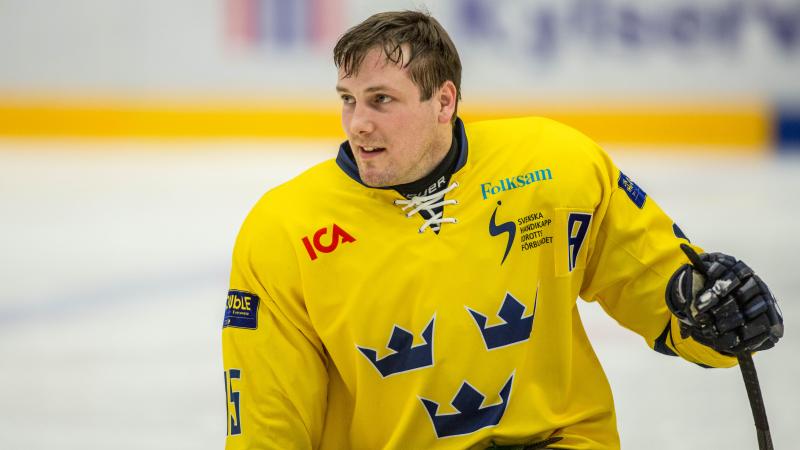 Swedish Para ice hockey player in his yellow Sweden jersey