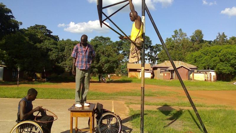 Three Ugandan men prepare the court for wheelchair basketball