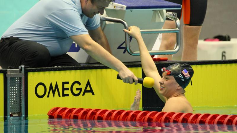 Women in pool giving an interview to someone at the pool edge