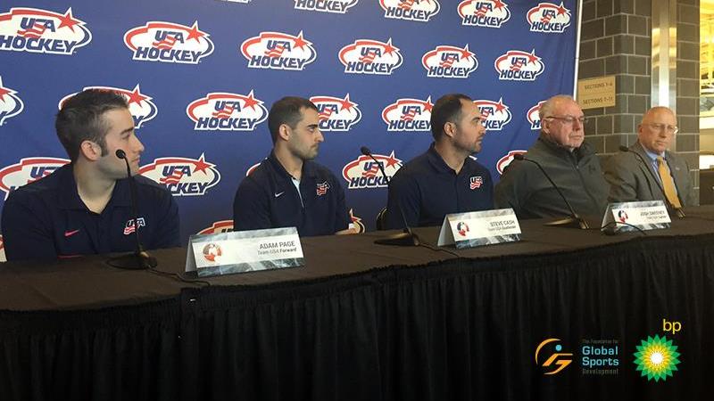 Three players and two men in training suits on a podium