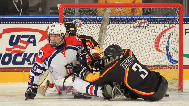 Two ice sledge hockey players fighting for the puck.