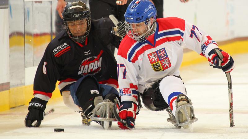 Two sledge hockey players fighting for the puk