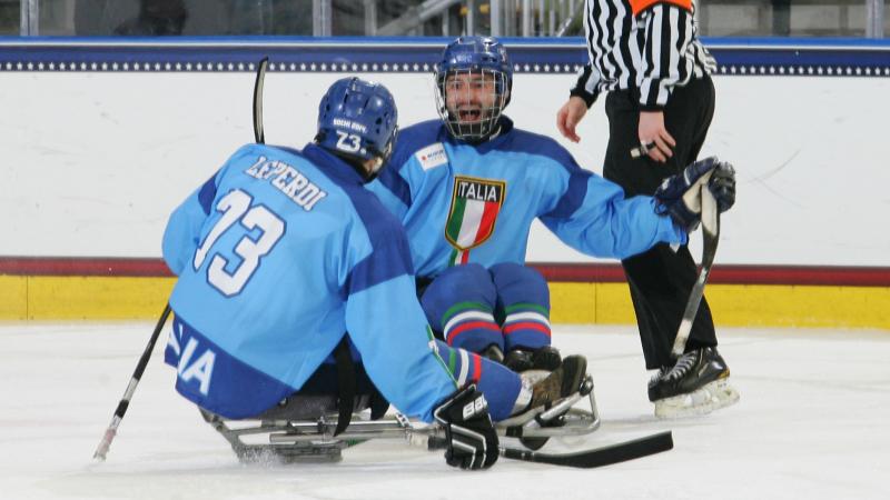 Two sledge hockey players in blue jerseys on the ice
