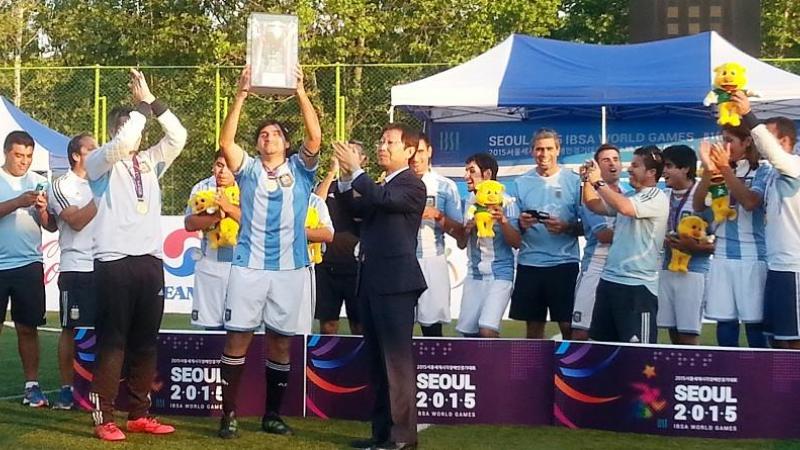 Group of men standing behind a banner holding a cup in the air.