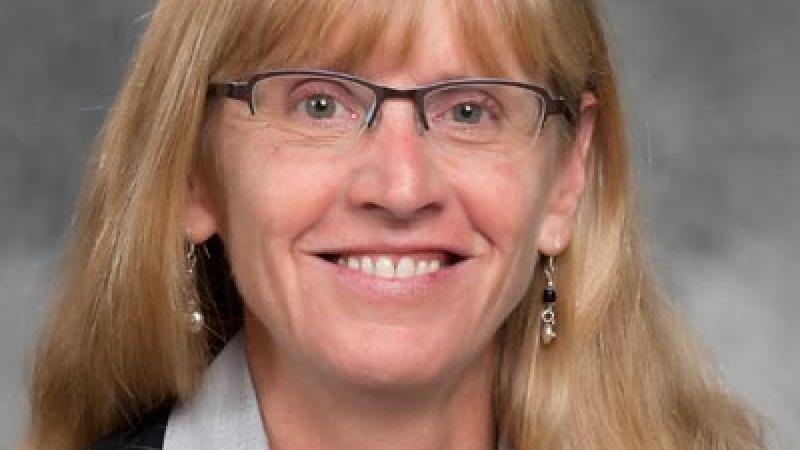 Portrait picture of a blonde woman, smiling to the camera