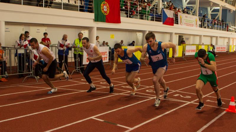 Five young men run on an athletics track next to each other