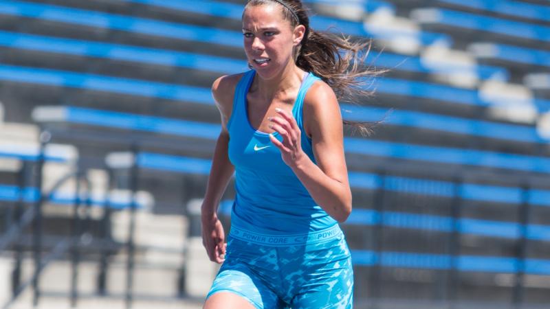 Women runs on a blue track, looks focused