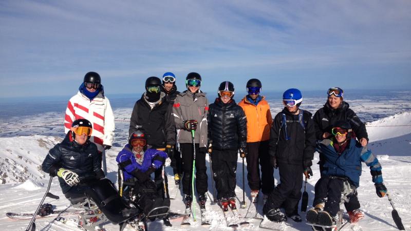 Group shot of skiers (sitting and standing) on a mountain