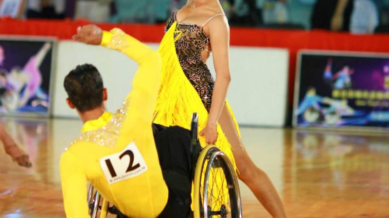 Man in wheelchair and woman standing pose while dancing