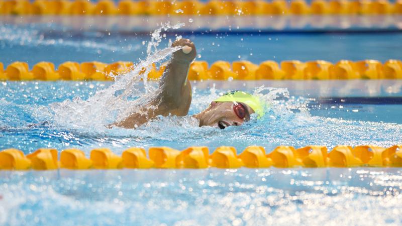 Swimmer with yellow cap doing freestyle.
