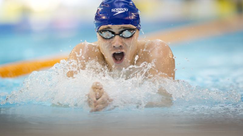 Swimmer with blue swim cap doing breaststroke