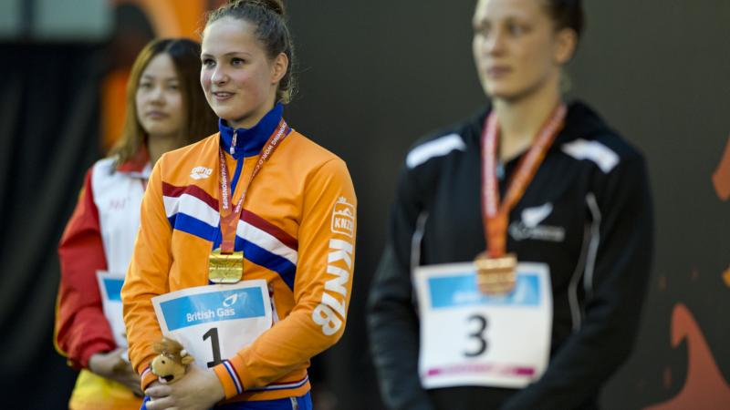 Three women in training suits on a podium