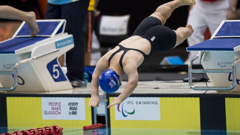 Swimmer with blue swim cap jumps off the start block.