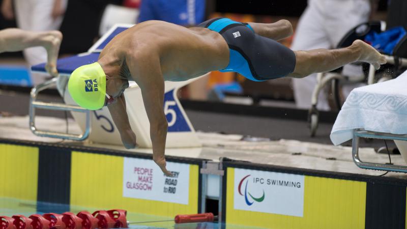 Swimmer with yellow swimp cap jumps of the blocks.