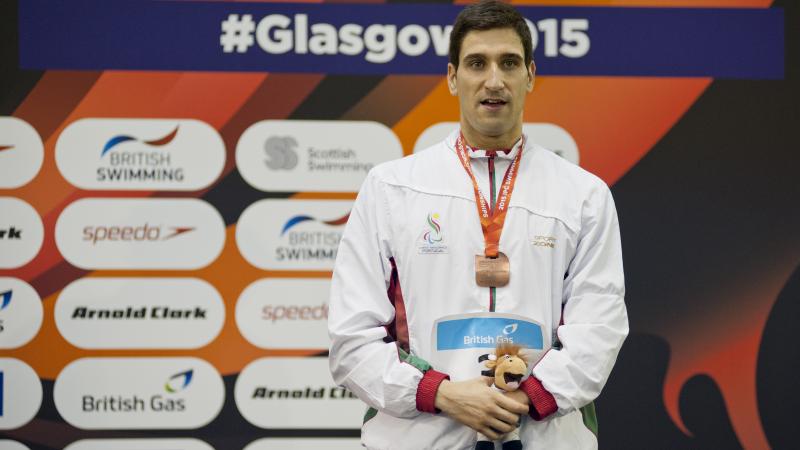 Man with medal around his neck standing on a podium