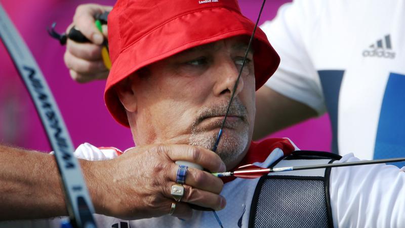 Close up of a man with a hat in an archery competition
