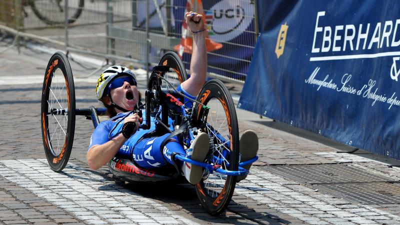 Woman on handbike crossing a finish line, celebrating