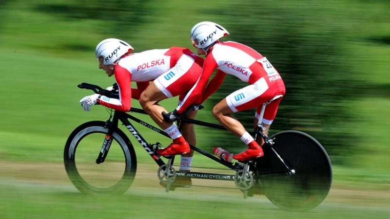 Two men cycling on a tandem in a race jersey