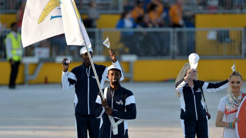 Man in a staduim, waving a flag followed by two other people