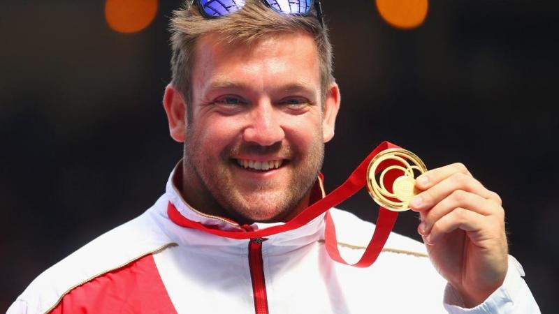 Gold medallist Dan Greaves of England poses on the podium during the medal ceremony for the Men's F42/44 Discus at Hampden Park during day five of the Glasgow 2014 Commonwealth Games 