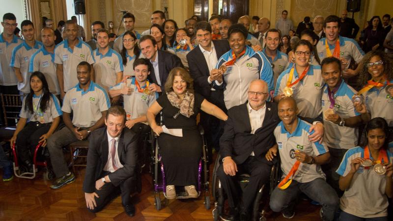 Group shot of athletes in Brazilian  team uniforms and some people in suits.