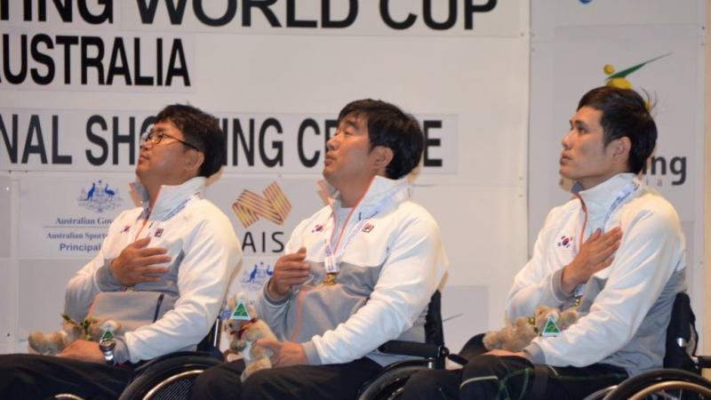 Three men in wheelchairs, having their hand on their chest